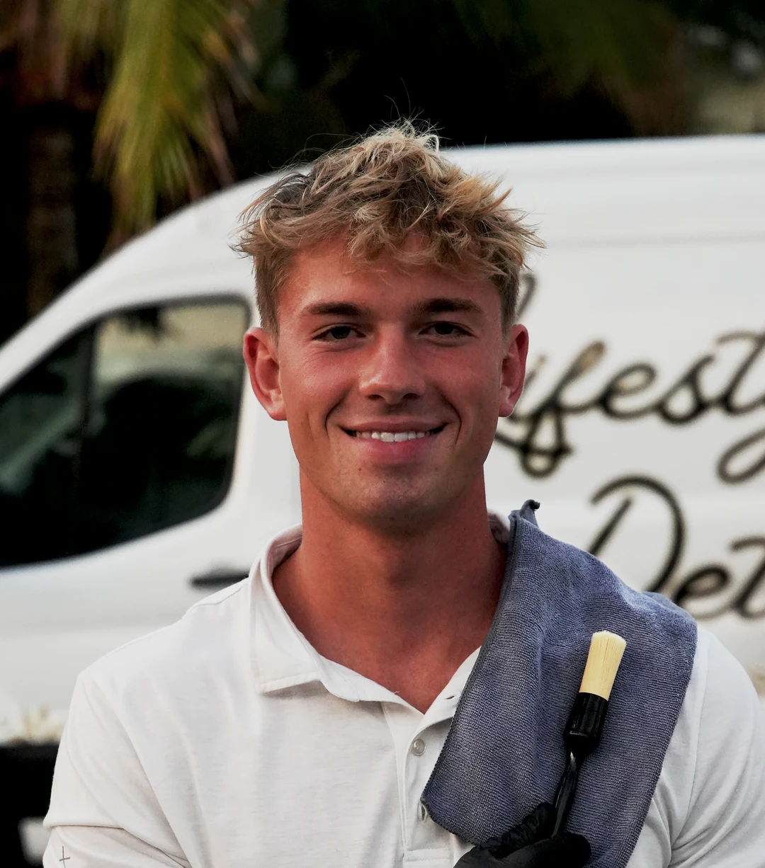 Chase S., owner of Lifestyle Mobile Detailing, smiling beside his detailing van with a towel over his shoulder