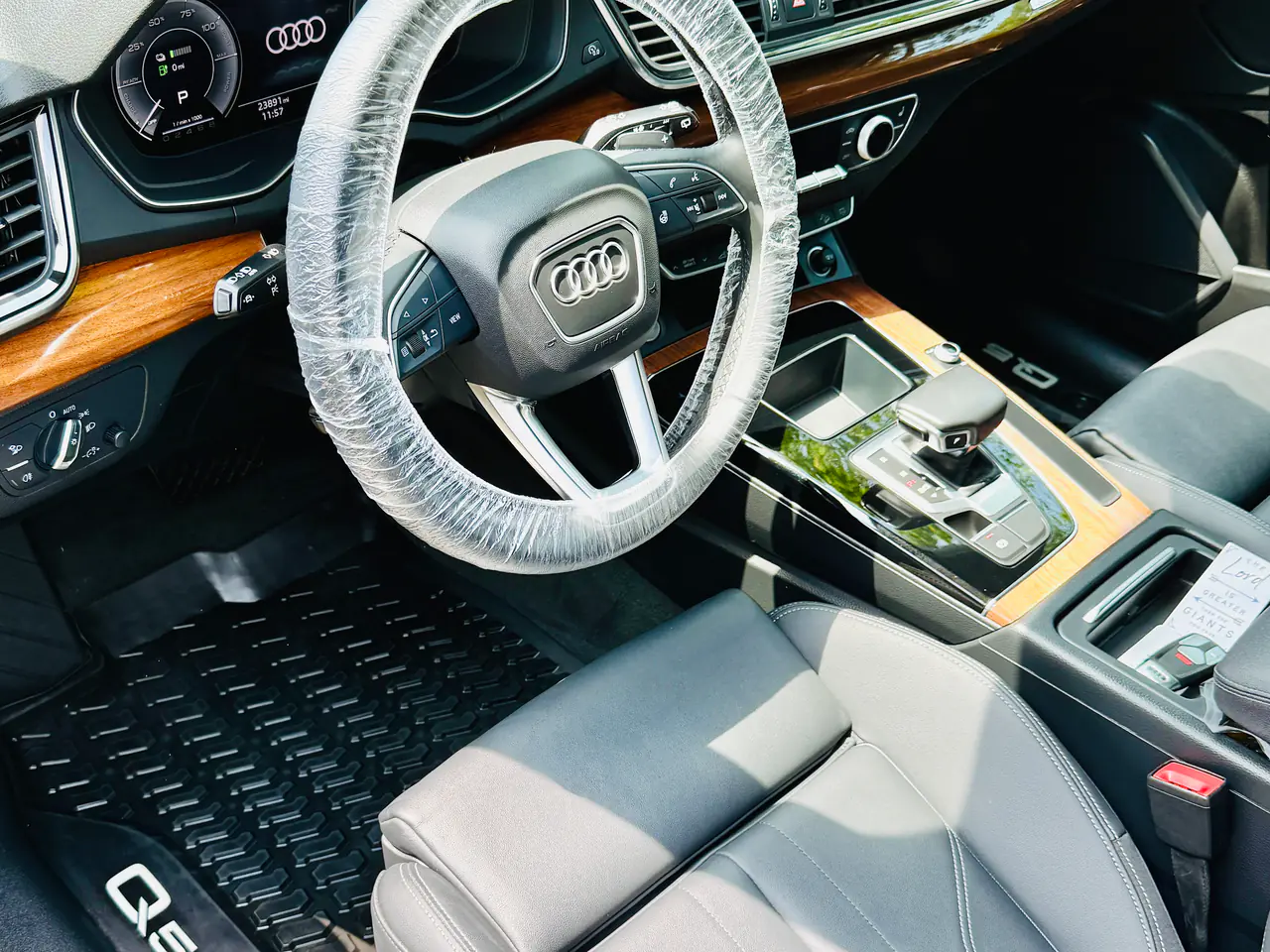 After an interior detail: the same Audi Q5's driver's side with a clean floor mat and the steering wheel wrapped