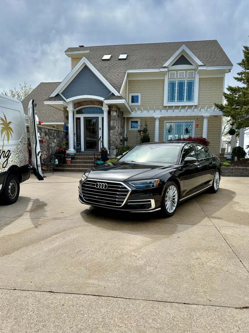 Black Audi A8 L after an exterior detail in front of a large stone-porch home