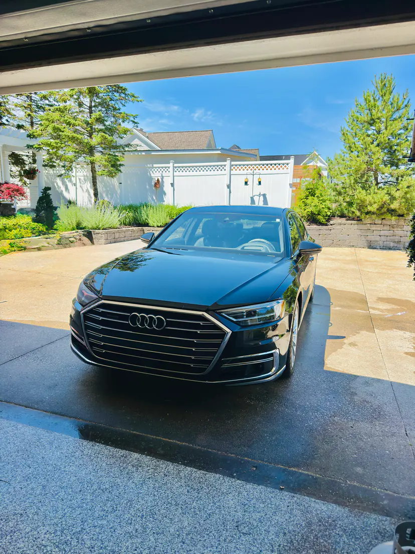 Black Audi A8 L after a mobile detail, seen from inside an open garage on a sunny day