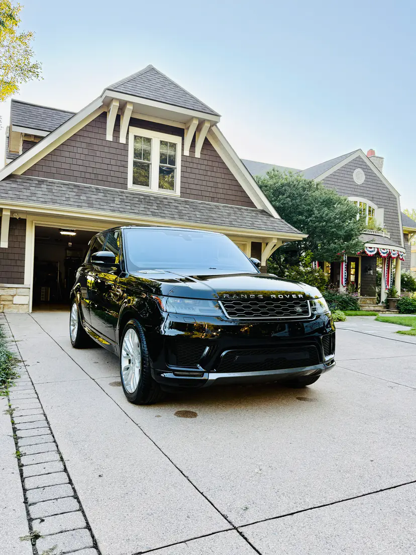 Black Range Rover Sport with a mirror-like gloss after an exterior detail in front of a craftsman home