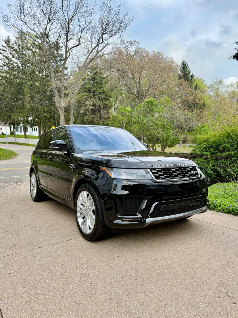 Black Range Rover Sport with a mirror gloss after an exterior detail on a quiet tree-lined drive