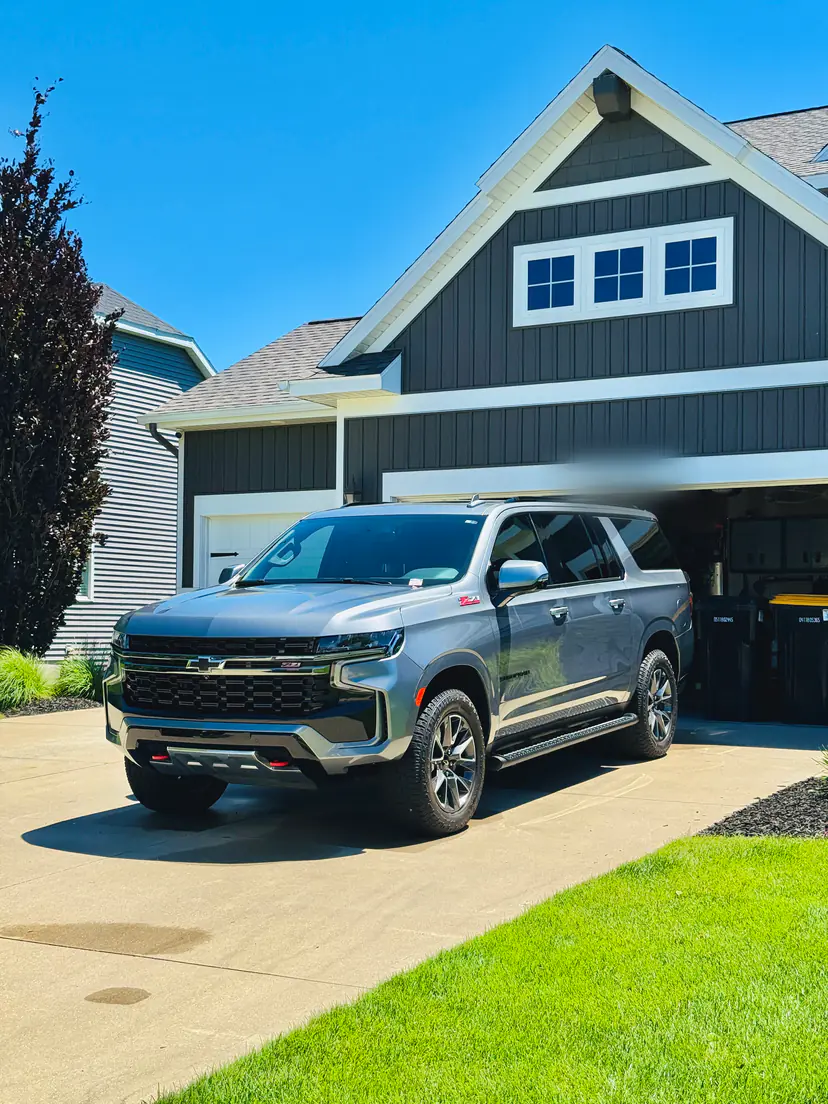 Grey Chevrolet Suburban Z71 after an exterior detail in front of a dark-sided family home