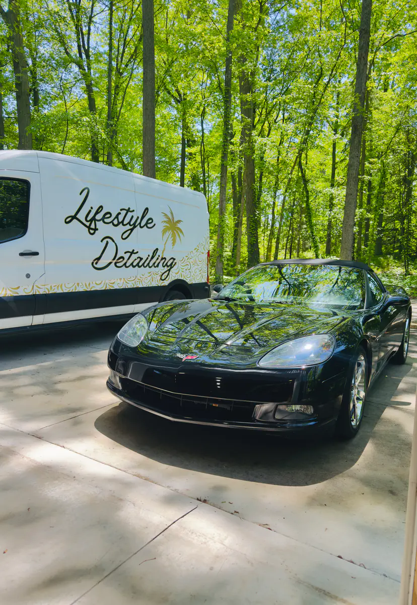 Black Chevrolet Corvette C6 after a detail beside the Lifestyle Detailing van, woods behind
