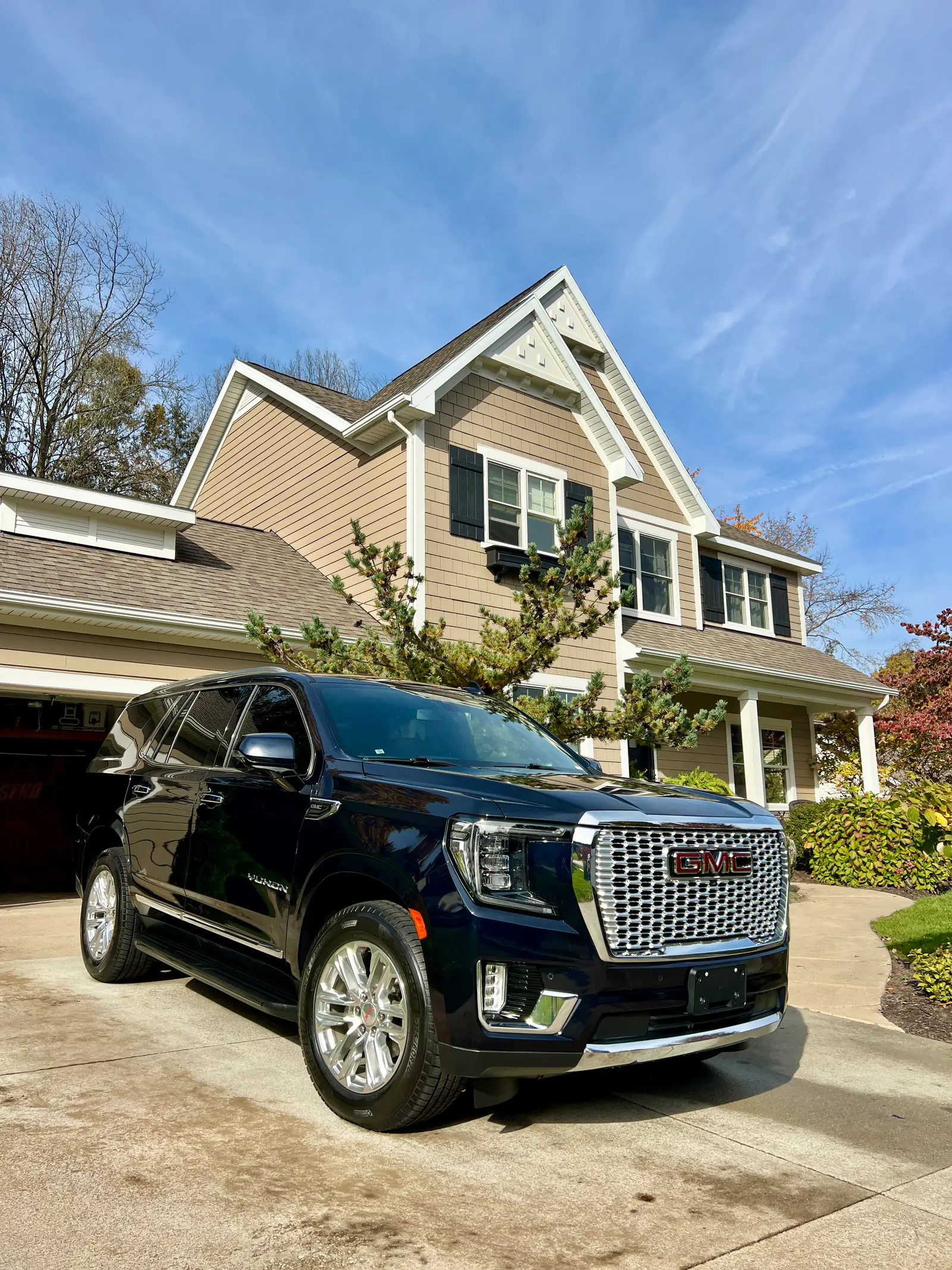 Navy GMC Yukon Denali with a deep, glossy finish after an exterior detail in front of a family home
