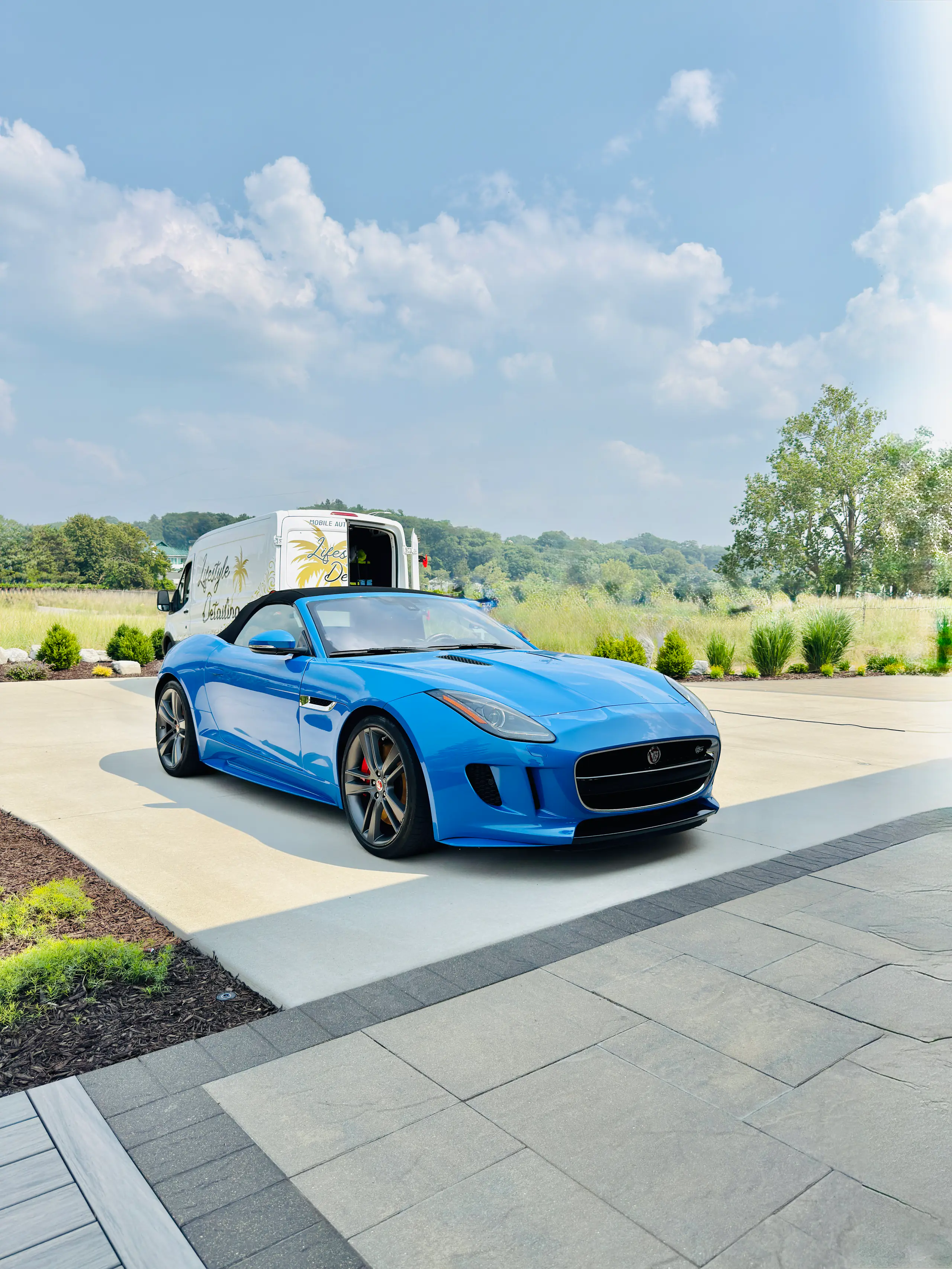 Blue Jaguar F-Type convertible after an exterior detail, the Lifestyle Detailing van parked behind it