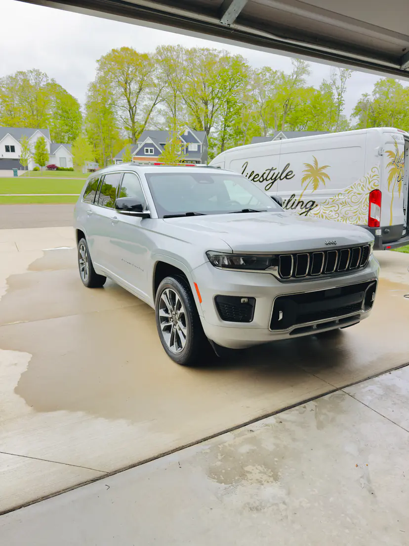 Silver Jeep Grand Cherokee L after a mobile detail in Georgetown Township, Michigan, seen from an open garage with the Lifestyle Detailing van beside it