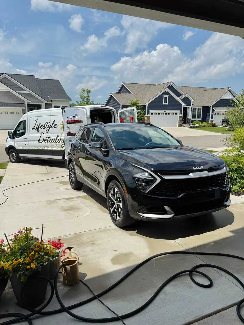 Black Kia Sportage after a mobile detail in Gaines Township, Michigan, the Lifestyle Detailing van parked behind it
