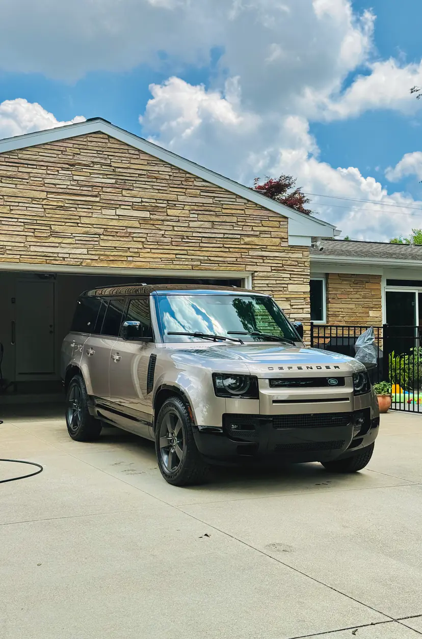 Land Rover Defender after an exterior detail, its glass and paint reflecting a bright summer sky