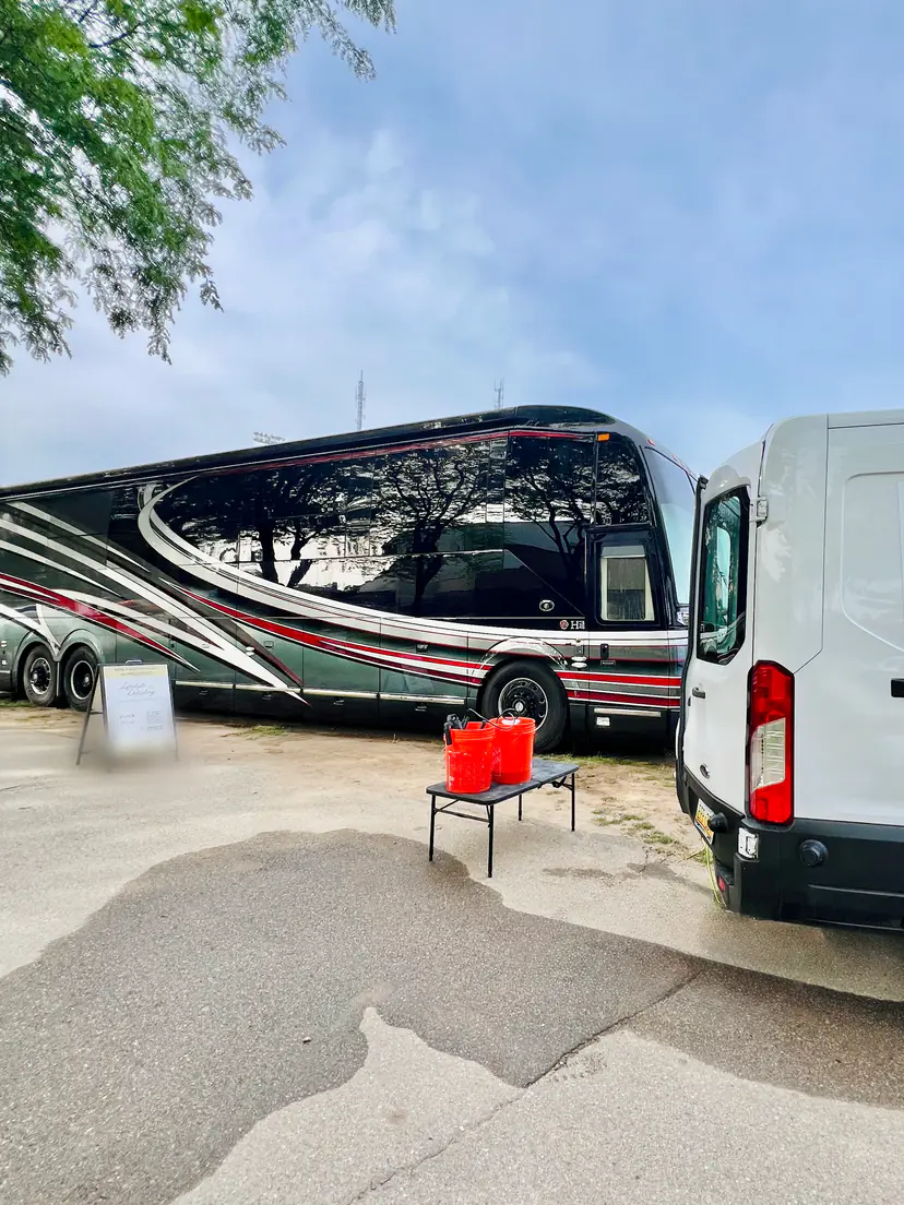 Luxury motorhome after an exterior detail, parked beside the Lifestyle Detailing van and its job-site sign