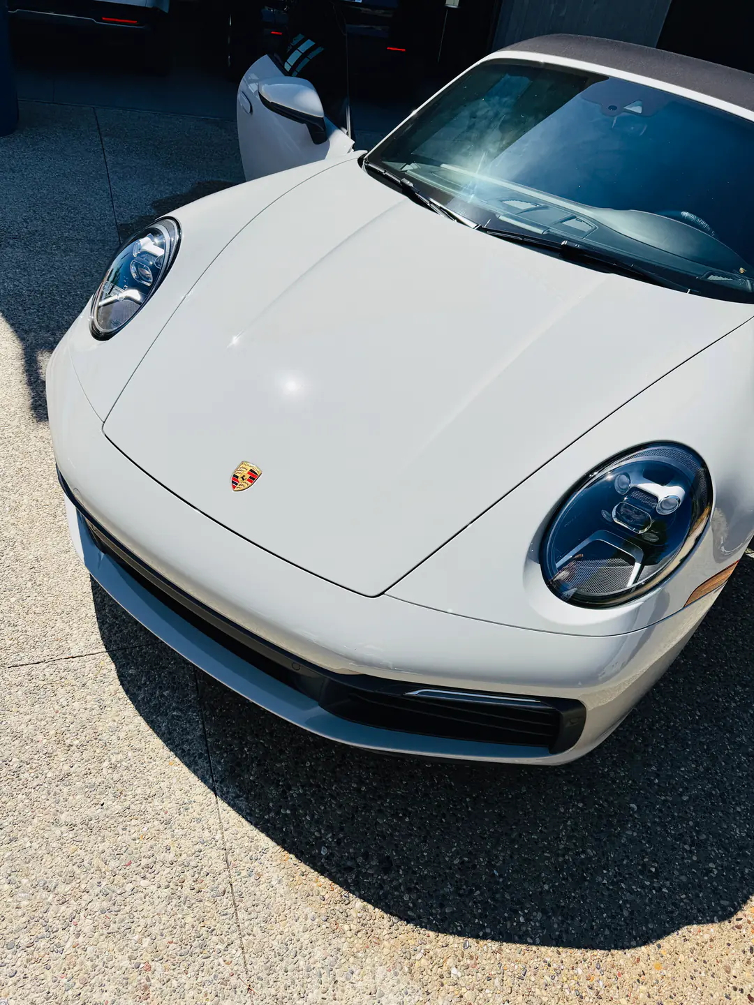 A white Porsche 911's hood and headlights with a protected, mirror-like gloss after detailing