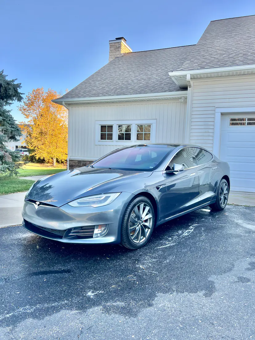 Grey Tesla Model S detailed in a home driveway, its clean paint catching the autumn light