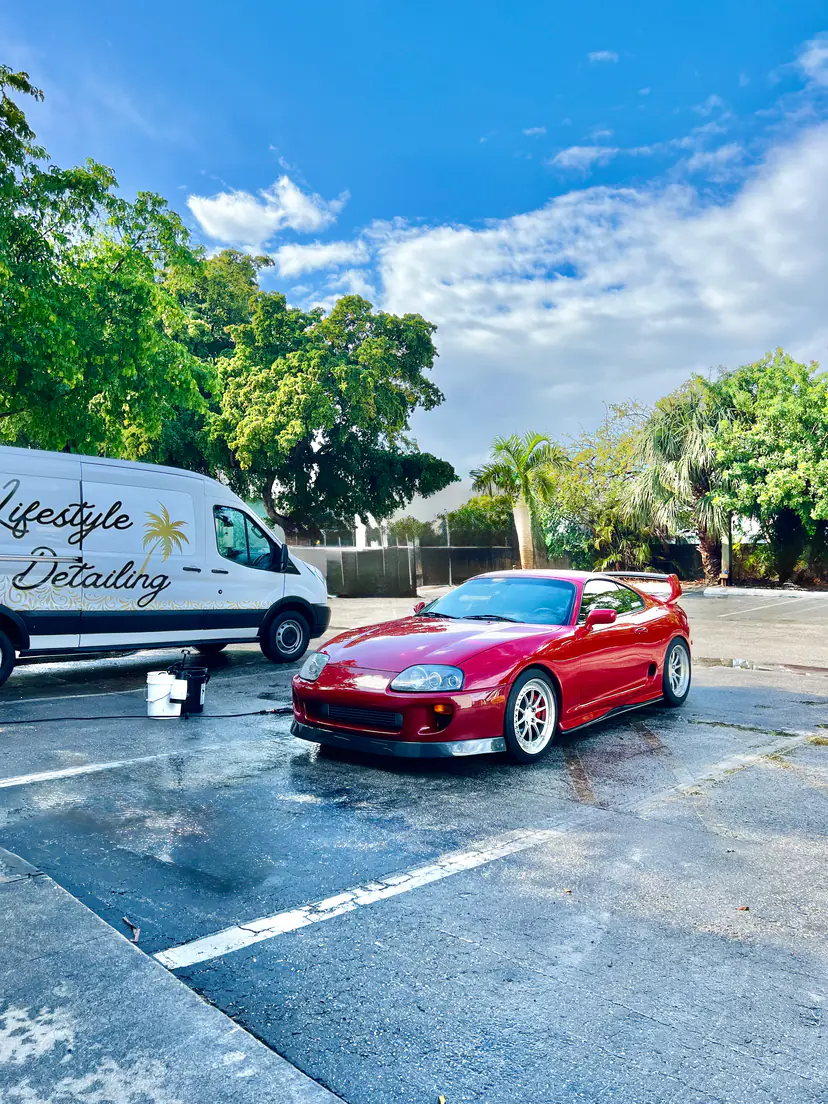 Red Toyota Supra parked beside the Lifestyle Detailing van after a mobile detail