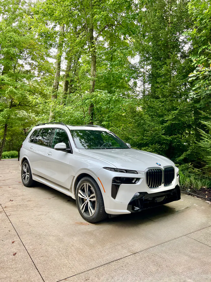 White BMW X7 after a full exterior detail on a wooded driveway