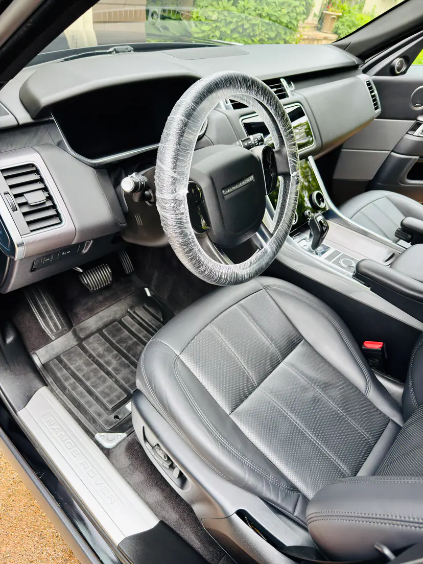 Range Rover Sport front cabin in black leather after a mobile interior detail, the steering wheel wrapped in protective film