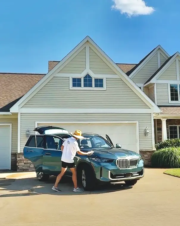 Chase Shooltz detailing a teal BMW X5 in front of a customer's home