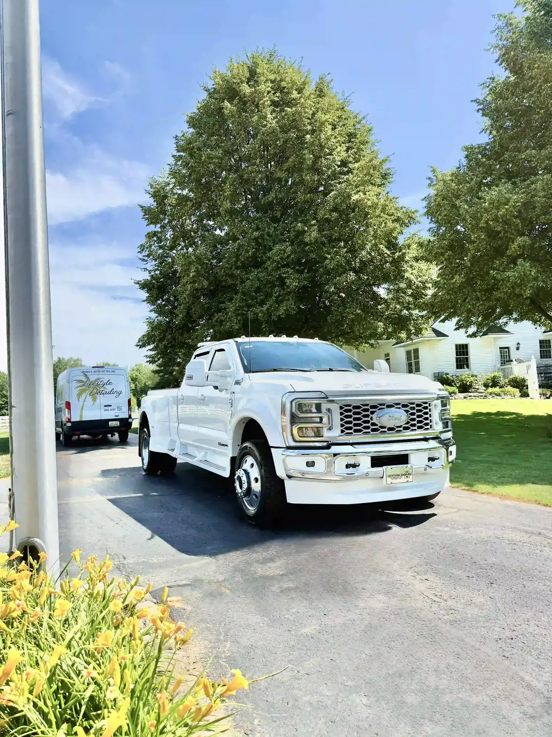 A white Ford dually pickup in a customer's driveway after paint correction